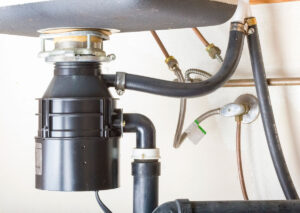 Under-sink garbage disposal unit with drain pipes and plumbing connections installed